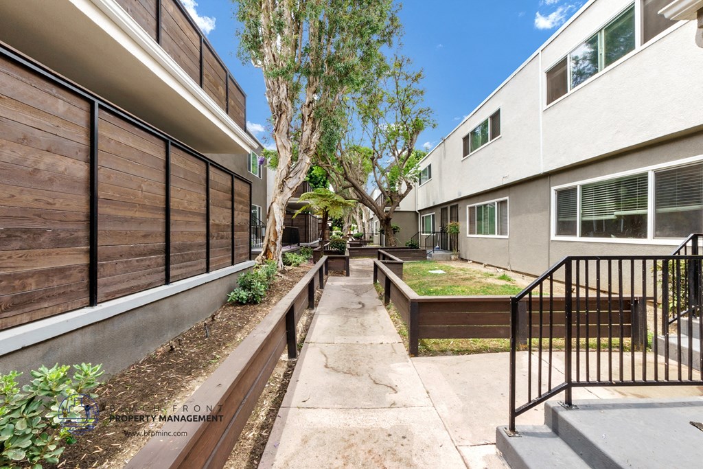 the courtyard between two apartment buildings with a tree in the middle