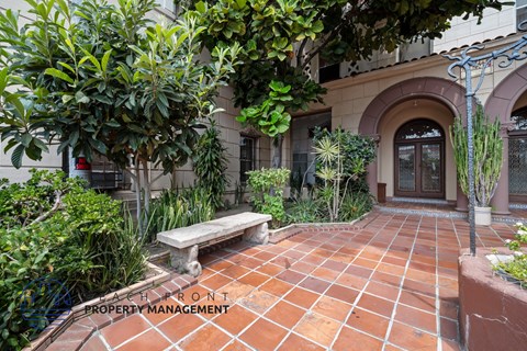 a courtyard with a bench and plants in front of a building