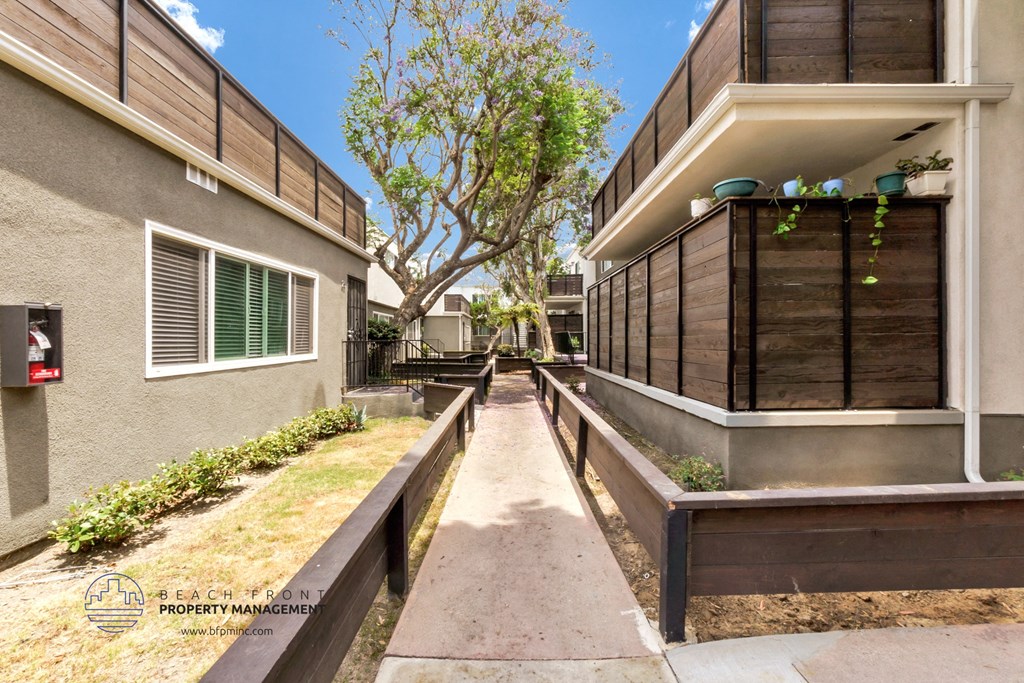 a house with a walkway between two buildings and a tree