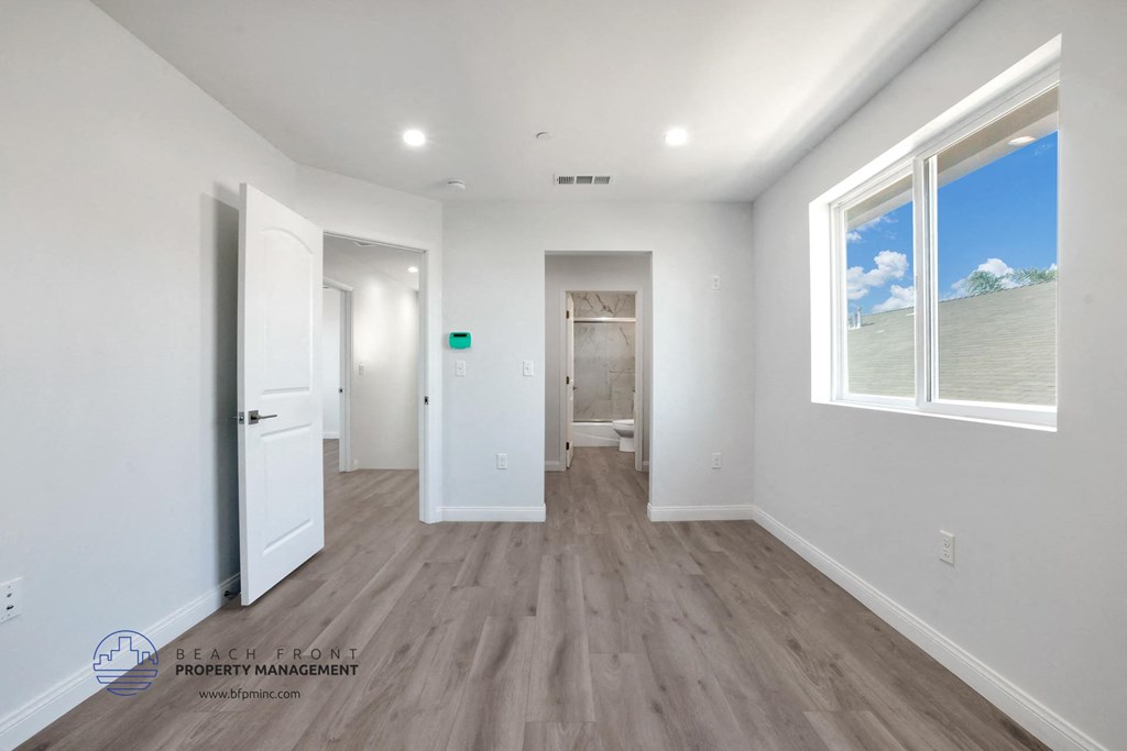 a renovated living room and hallway with white walls and wood flooring