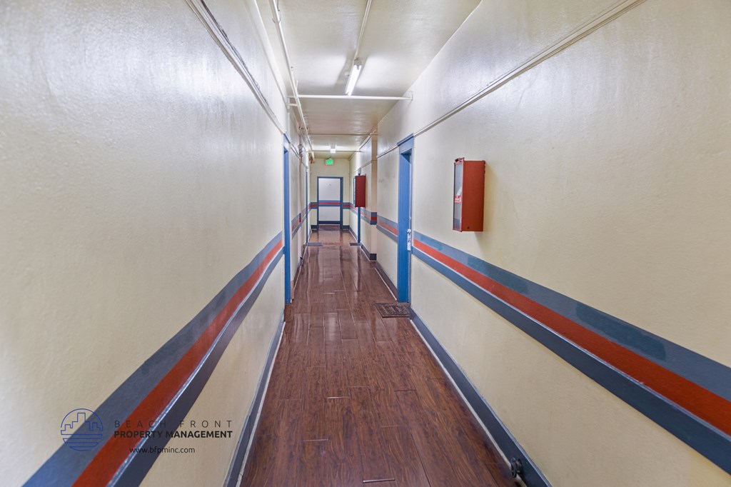 a corridor with white walls and blue and red stripes on the floor and a wood