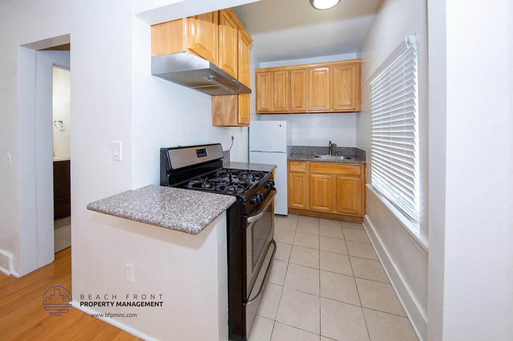 a kitchen with a stove and a sink and wooden cabinets