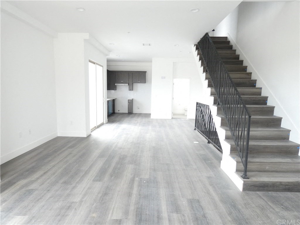 a large empty living room with a staircase and white walls and wood floors