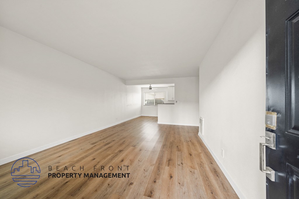 A long, empty hallway with a logo for Beach Front Property Management in the bottom left corner.