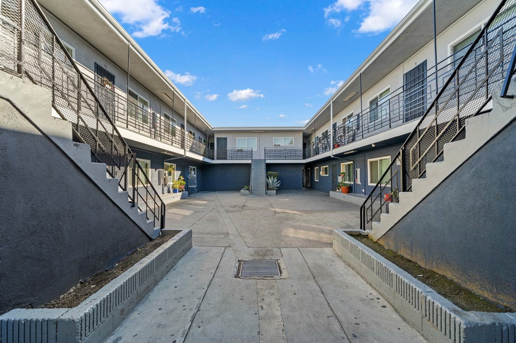an empty parking lot between two buildings with stairs