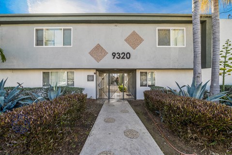 The image shows a building with the number 9320 on it, surrounded by greenery and a clear sky.