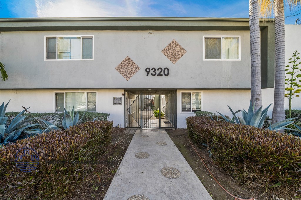 the front of an apartment building with a sidewalk and palm trees