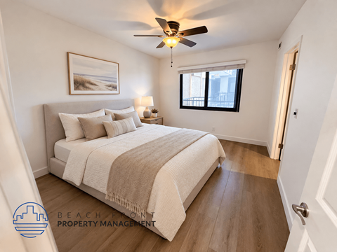 A bedroom with a bed, a ceiling fan, and a painting on the wall.