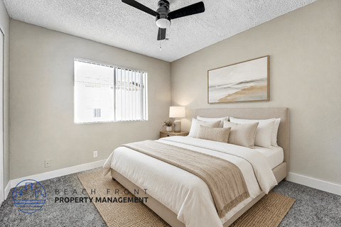 A well-lit bedroom with a large bed and a ceiling fan.