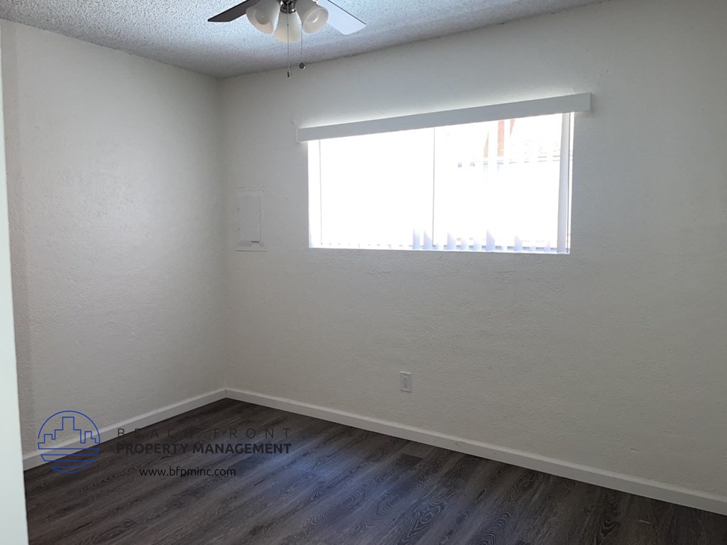a bedroom with a window and wooden floors and a ceiling fan