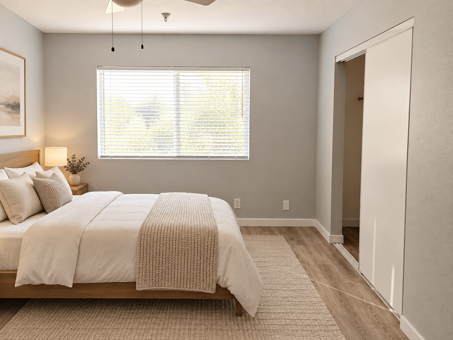 A bedroom with a large bed and a window with blinds.