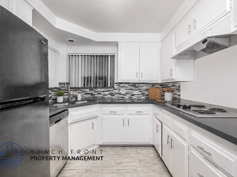 A kitchen with white cabinets and a black refrigerator.