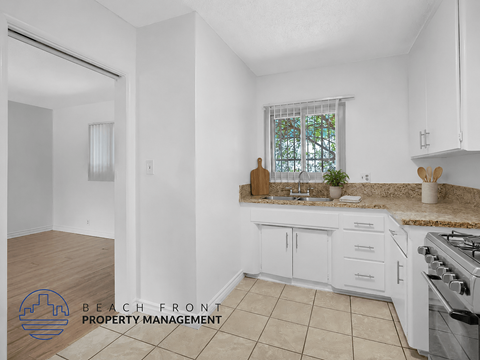 A kitchen with white cabinets and a tiled floor.