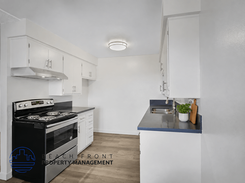 A modern kitchen with a black stove top oven and white cabinets.