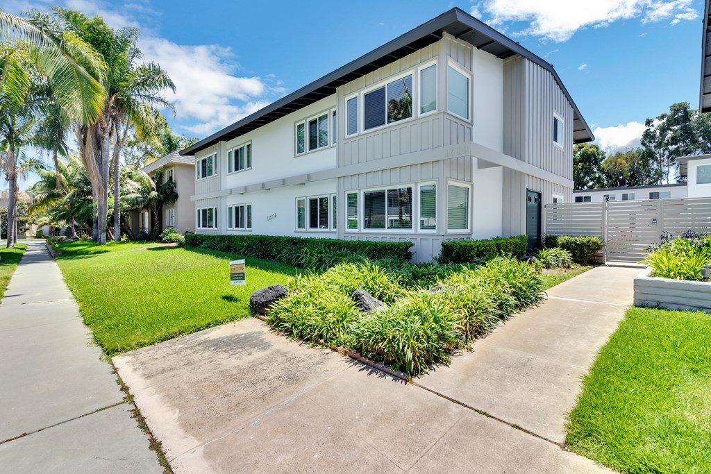 A modern two-story house with a white exterior and a landscaped front yard.