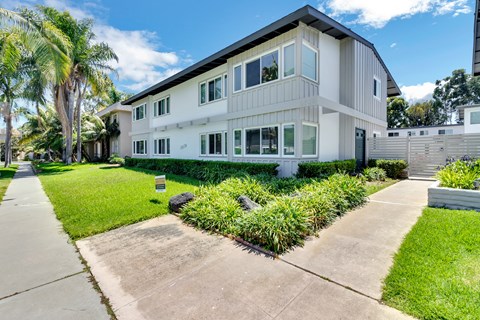 A modern two-story house with a white exterior and a landscaped front yard.