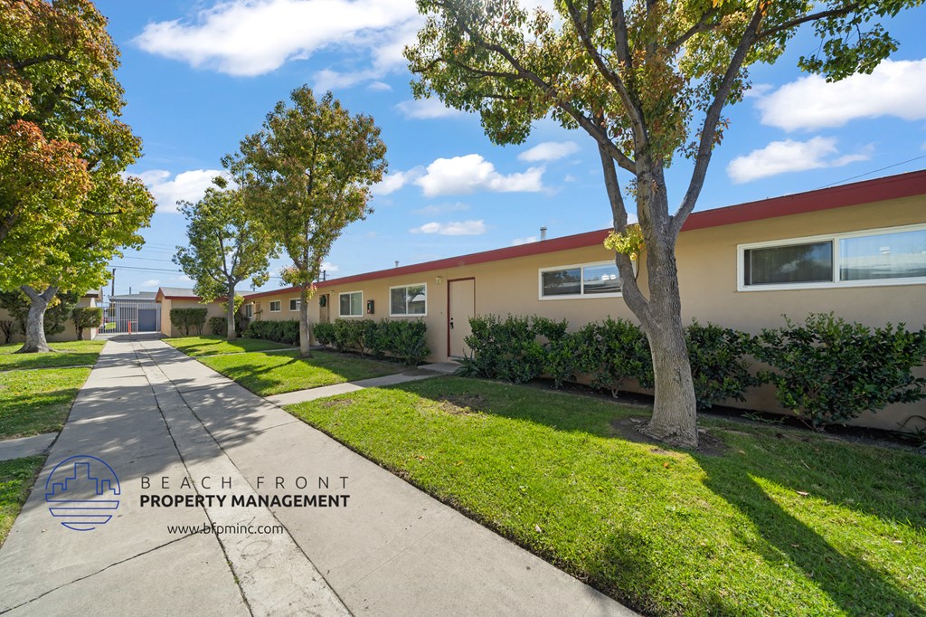a long row of houses with a sidewalk and trees in front of them