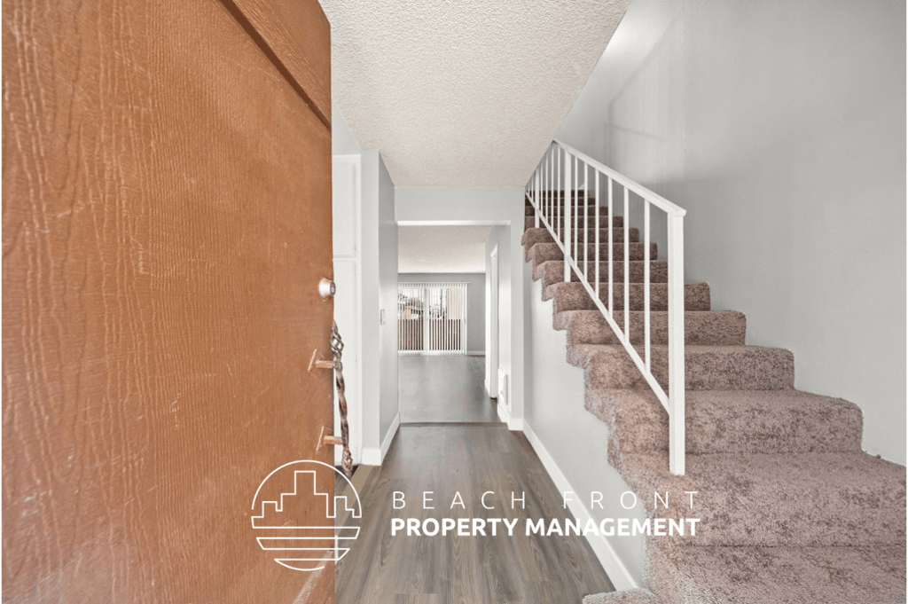 a view of the hallway of a house with stairs and a hallway with a door