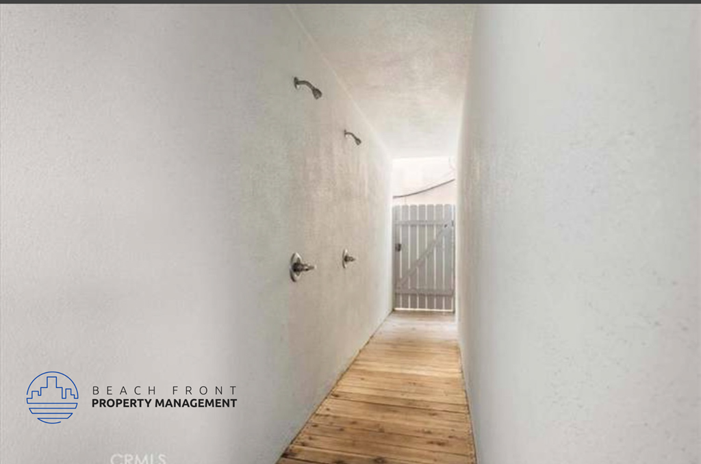 a hallway with white walls and wooden floors and a balcony