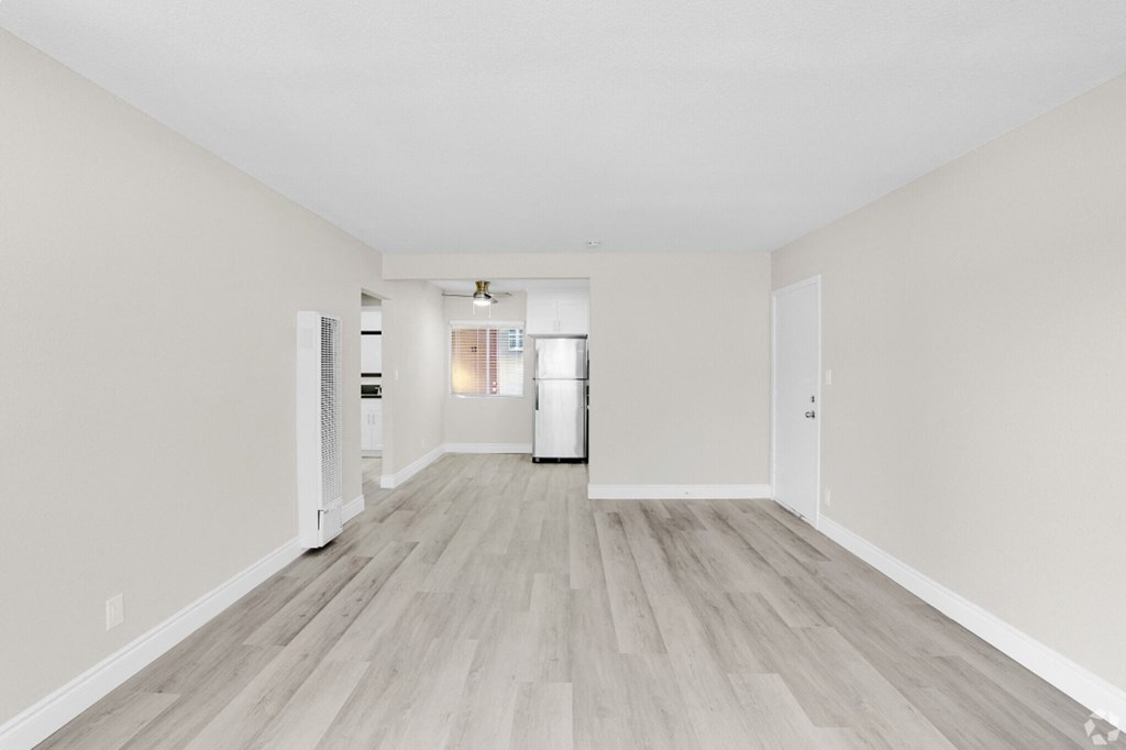 a spacious living room with white walls and wood floors