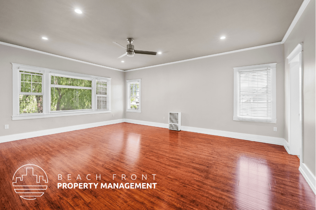 an empty living room with wood floors and a ceiling fan