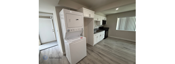 A white dishwasher is in a kitchen with wood flooring.