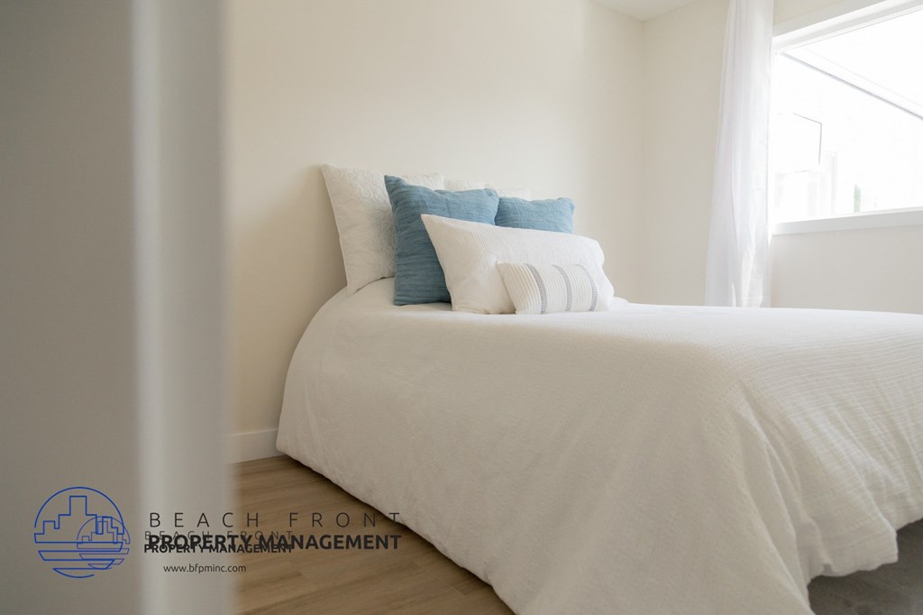A white bed with a white headboard and a white pillow with a blue pillow on it.