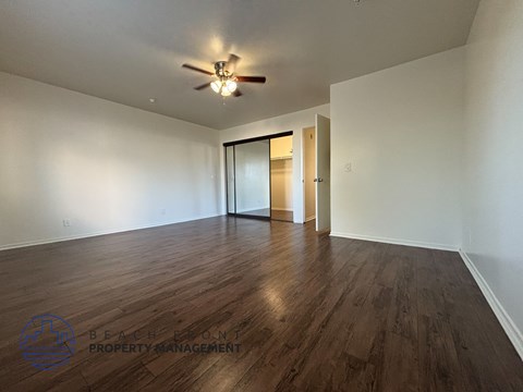 A spacious room with wooden floors and a ceiling fan.