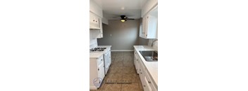 A kitchen with white cabinets and a tile floor.