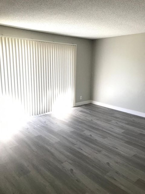A room with wooden flooring and a window with blinds.