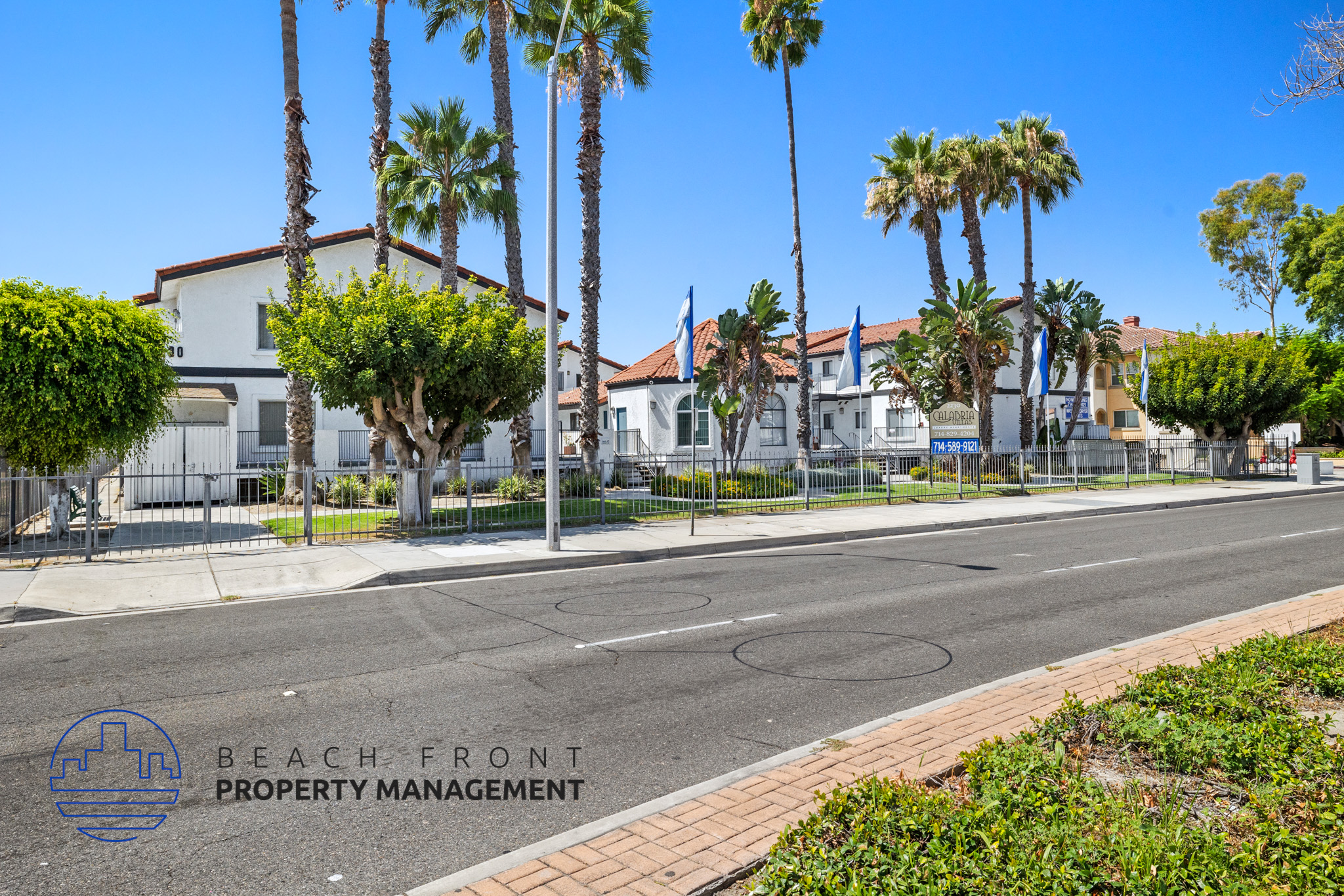 A street view with palm trees and a sign for Beach Front Property Management.