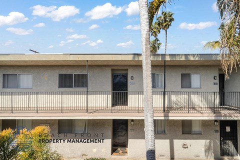 A building with a balcony and a palm tree in front of it.