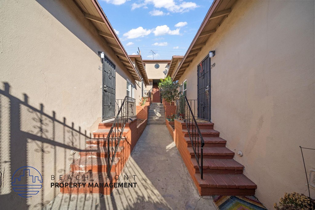 A staircase with a metal railing and steps leading up to a door with a black gate.