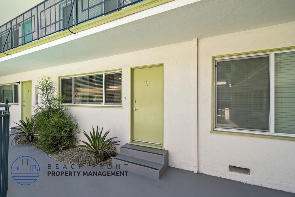 A building with a yellow door and a sign that says Beachfront Property Management.
