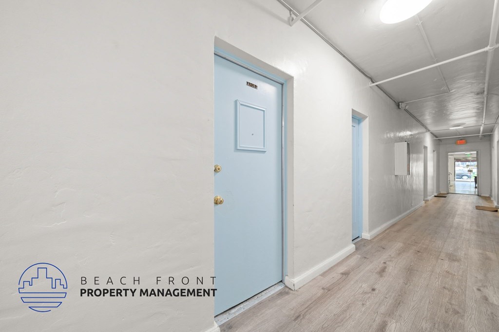 A hallway with a blue door and a logo for Beach Front Property Management.