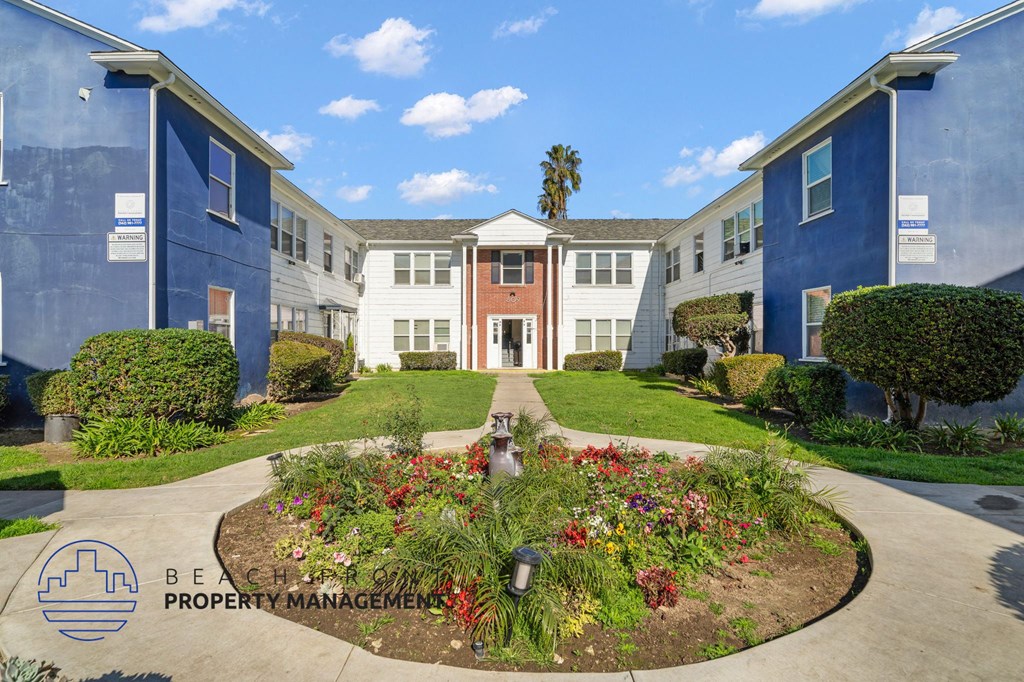 A garden in front of a building with the logo of Beachfront Property Management.