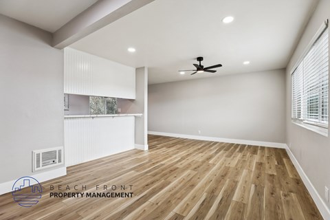 A spacious room with wooden flooring and a ceiling fan.
