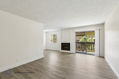 A spacious living room with a fireplace and sliding glass doors leading to a balcony.