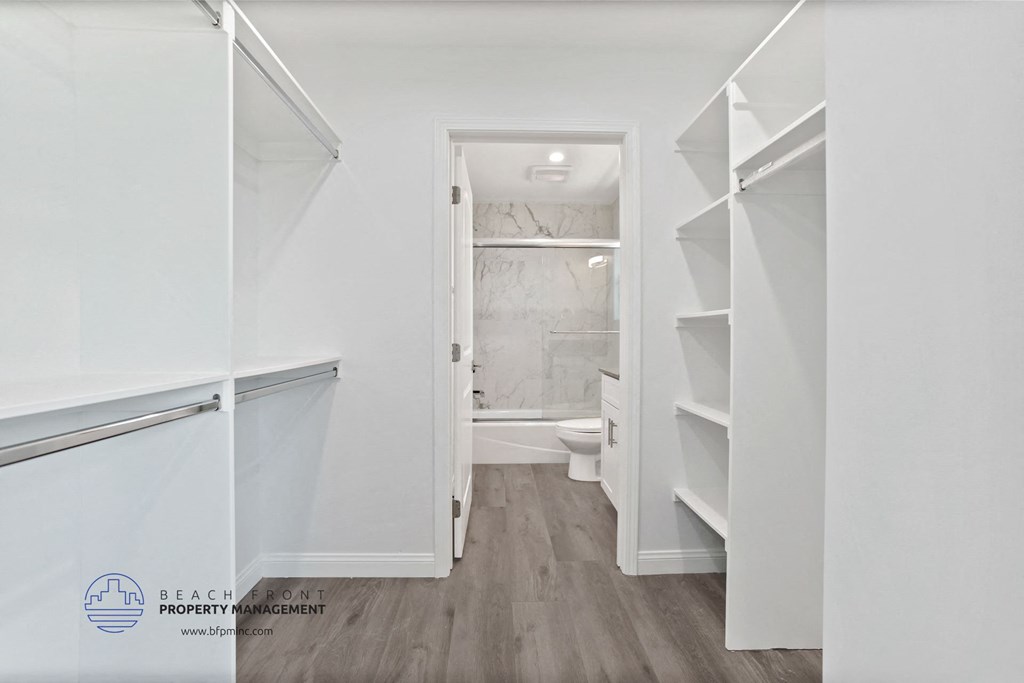 a walk in closet in a white bathroom with a toilet and shelves