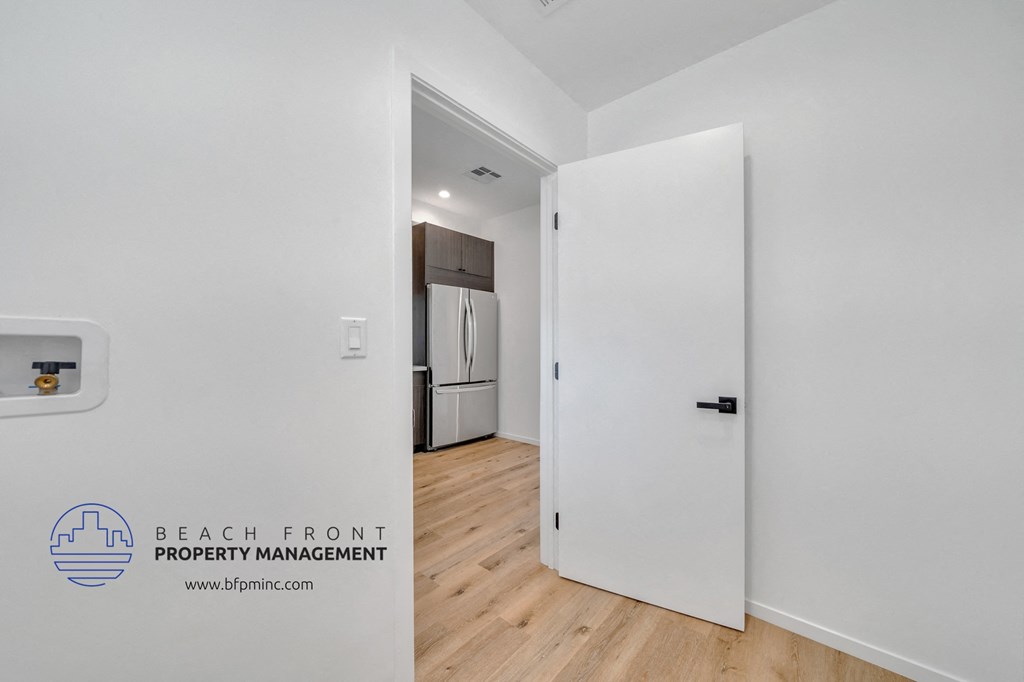 a renovated living room with white walls and a door to the kitchen