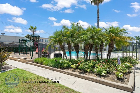 A pool area with a fence and a sign that says Beachfront Property Management.