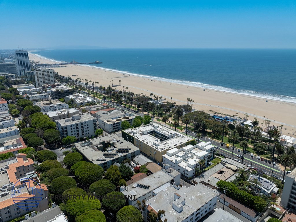 A beachfront cityscape with buildings, trees, and a sandy beach.