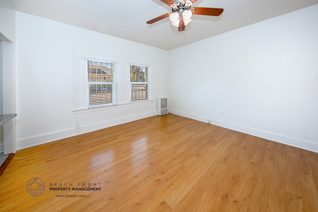 the living room of a home with wood floors and a ceiling fan