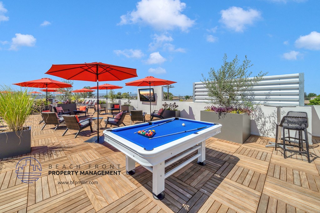 a rooftop patio with a pool table and umbrellas