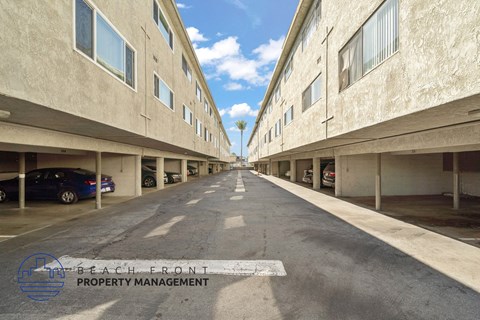 A long, empty parking garage with a logo for Beach Front Property Management in the bottom left corner.