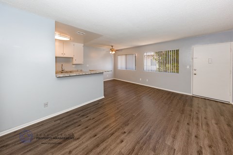 A spacious room with wooden flooring and white walls.