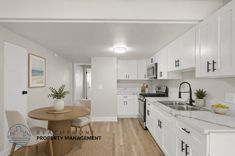 A kitchen with white cabinets and a round table with chairs.