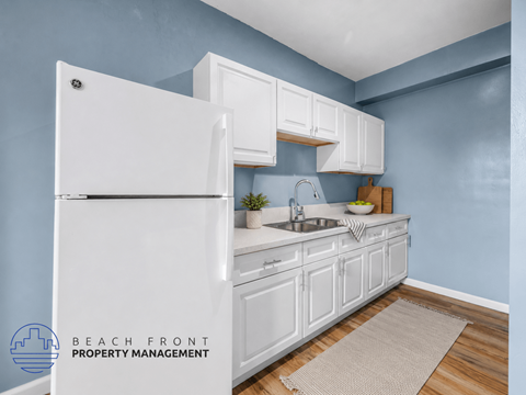A kitchen with white cabinets and a white refrigerator.