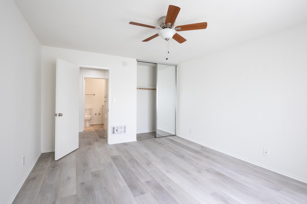 A room with a ceiling fan and light, and a doorway leading to another room.
