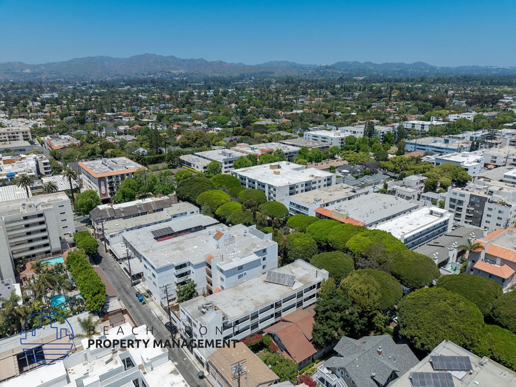A bird's eye view of a city with buildings, trees, and a clear sky.